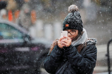 A woman takes photographs as snow falls in the Times Square neighborhood of New York, U.S., February 12, 2019. REUTERS/Lucas Jackson