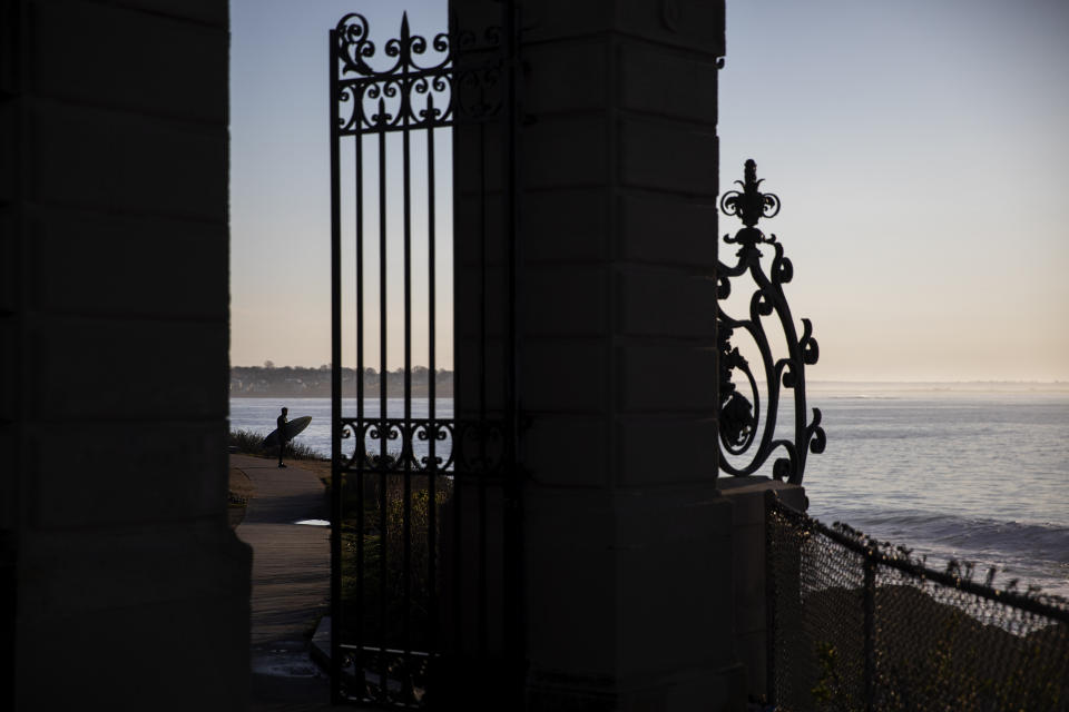 FILE - In this April 25, 2020, file photo, a surfer looks out over the waves off the cliffs of Newport, R.I., as shutdown orders are still in place during the coronavirus outbreak. (AP Photo/David Goldman, File)