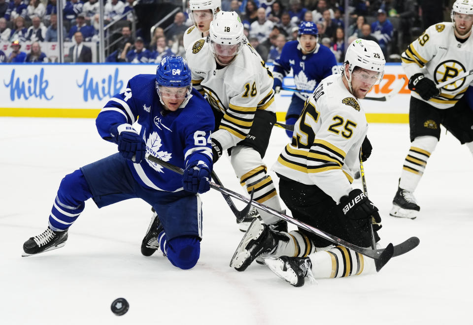Toronto Maple Leafs' David Kampf (64) battles with Boston Bruins' Pavel Zacha (18) and Brandon Carlo (25) during second-period action in Game 4 of an NHL hockey Stanley Cup first-round playoff series in Toronto, Saturday, April 27, 2024. (Frank Gunn/The Canadian Press via AP)