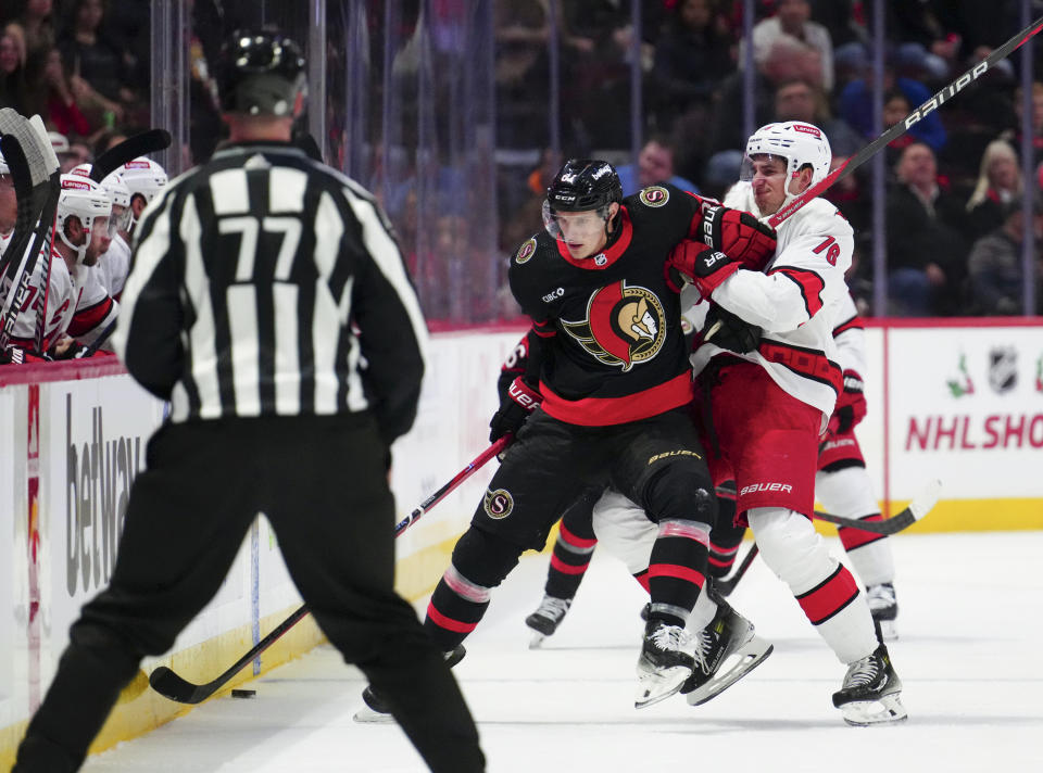 Ottawa Senators left wing Dominik Kubalik (81) and Carolina Hurricanes defenseman Brady Skjei (76) battle for the puck during the first period of an NHL hockey match in Ottawa, Ontario, on Tuesday, Dec. 12, 2023. (Sean Kilpatrick/The Canadian Press via AP)