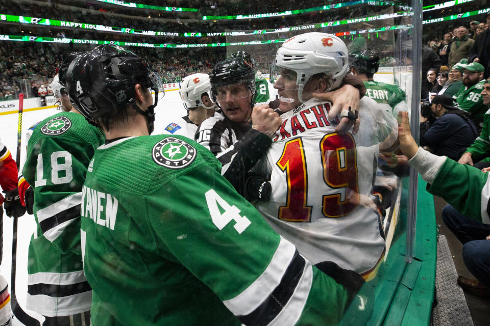 Dallas Stars defenseman Miro Heiskanen (4) and Calgary Flames left wing Matthew Tkachuk (19) are separated by an official during the second period of an NHL hockey game, Sunday, Dec. 22, 2019, in Dallas. (AP Photo/Sam Hodde)