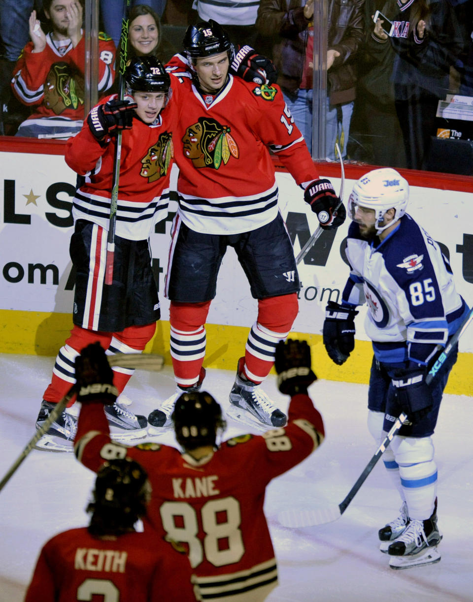 Chicago Blackhawks' Artem Anisimov (15) of Russia, celebrates with teammates Artemi Panarin (72) of Russia, and Patrick Kane (88) after scoring a goal while Winnipeg Jets' Mathieu Perreault (85) looks on during the second period of an NHL hockey game Tuesday, Dec. 27, 2016, in Chicago. (AP Photo/Paul Beaty)