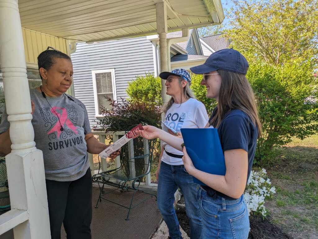 Two volunteers speak to a voter on their porch as they talk about the upcoming election to fill a seat on the North Carolina Supreme Court.