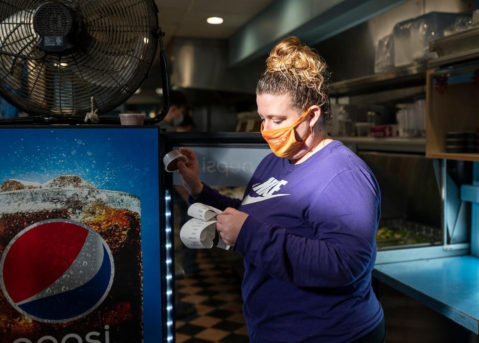 Kristin Williamson prepares lunch orders at Spoodles Deli in Worcester Wednesday.