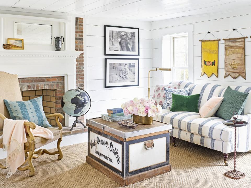 a living room with a striped couch and white shiplap walls