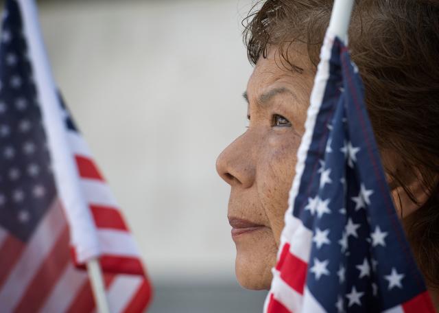 A woman holds a US flag as members of the November 2020 Coalition protest outside the Federal Building calling for the Trump administration to close border camps, free immigrant children and allow legal representation, in Los Angeles, September 16, 2019. (Photo by Mark RALSTON / AFP)        (Photo credit should read MARK RALSTON/AFP via Getty Images)