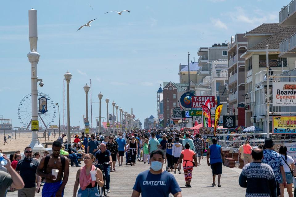 Vistors, many without masks, walk the beachfront boardwalk