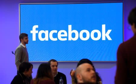 FILE PHOTO - People stand in front of a logo at Facebook's headquarters in London, Britain, December 4, 2017. REUTERS/Toby Melville