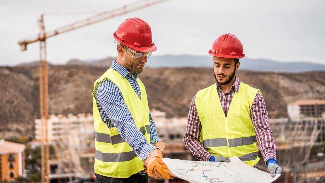 Builders on residential construction site looking the building project  - Workers are satisfied of their plan - Dealing, real estate, engineer and industrial concept - Focus on left man face.