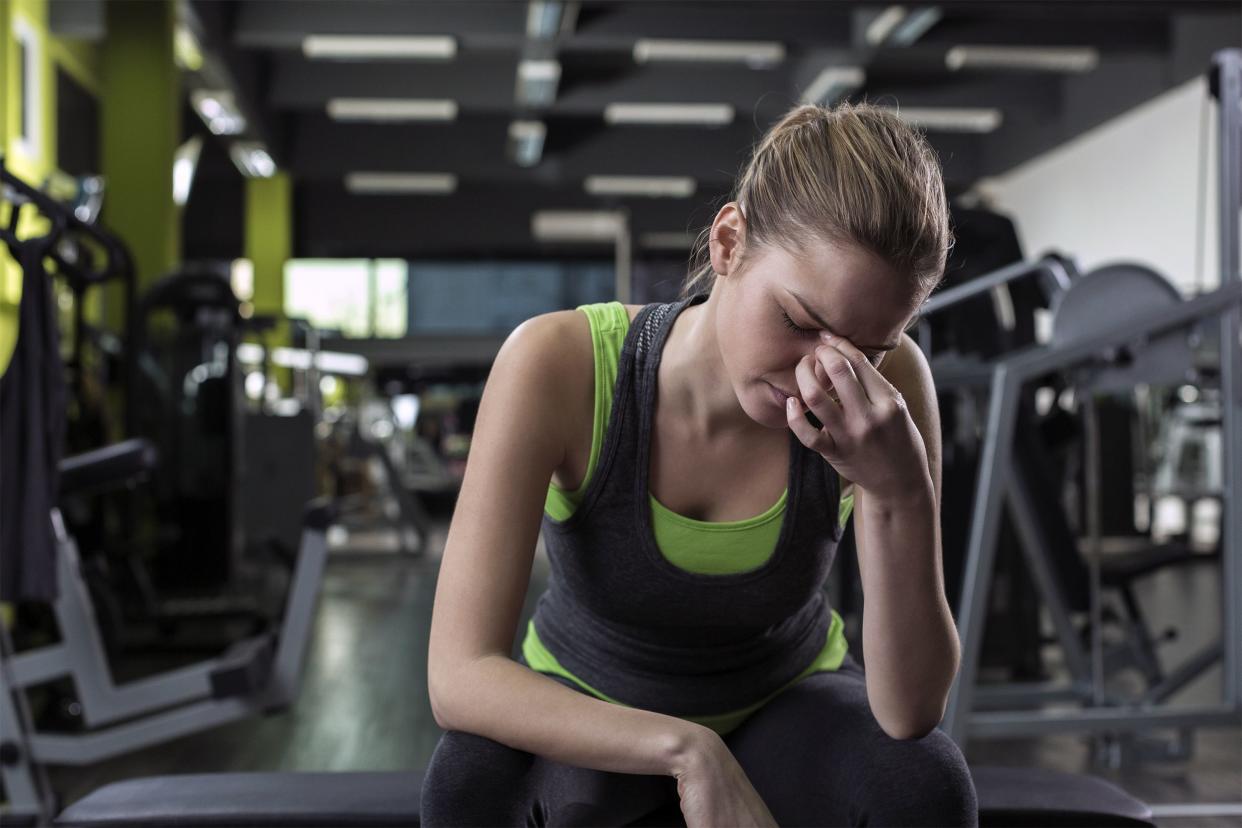 Woman sitting at the gym holding her head