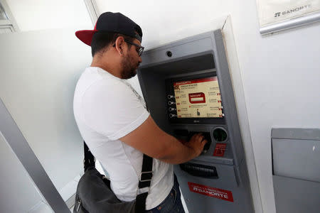 Mexican student Kevin, 20, withdraws a money transfer from an ATM machine, sent by his mother who lives in the United States, in Mexico City, Mexico, March 31, 2016. REUTERS/Edgard Garrido