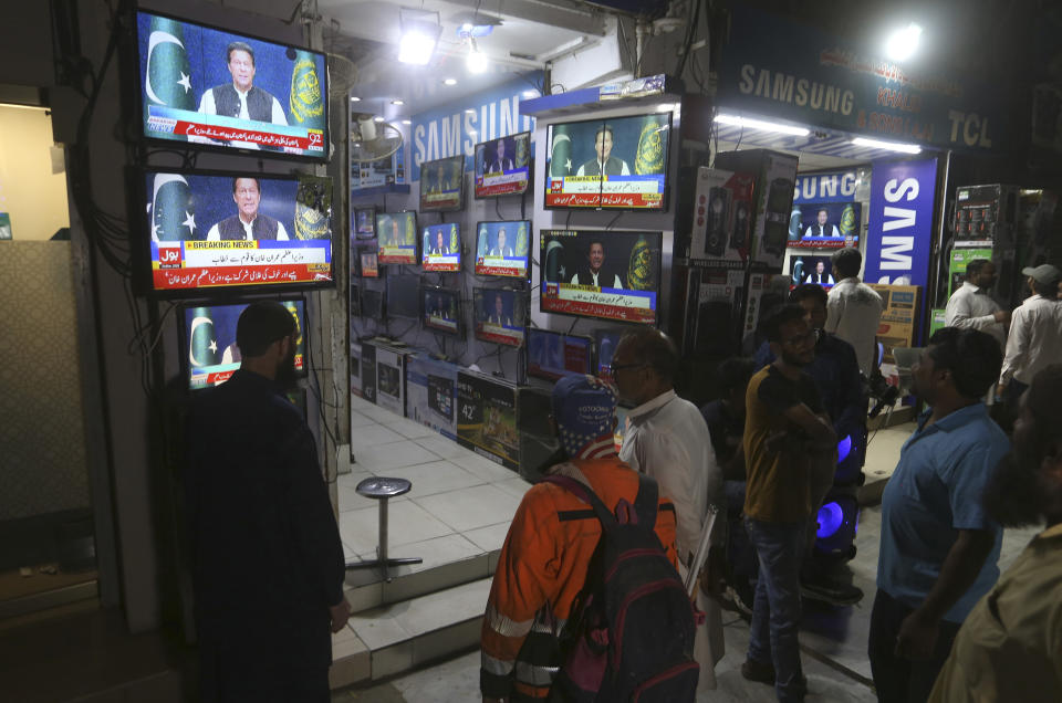 People watches news channels broadcast a live address to the nation by Pakistan's Prime Minister Imran Khan at a market, in Karachi, Pakistan, Thursday, March 31, 2022. Pakistan's embattled Prime Minister Khan remained defiant on Thursday, telling the nation that he will not resign even as he faces a no-confidence vote in parliament and the country's opposition says it has the numbers to push him out. (AP Photo/Fareed Khan)