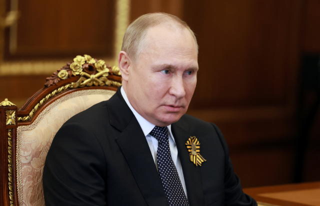 Vladimir Putin, seated in a gilded chair, his face looking a little bloated.