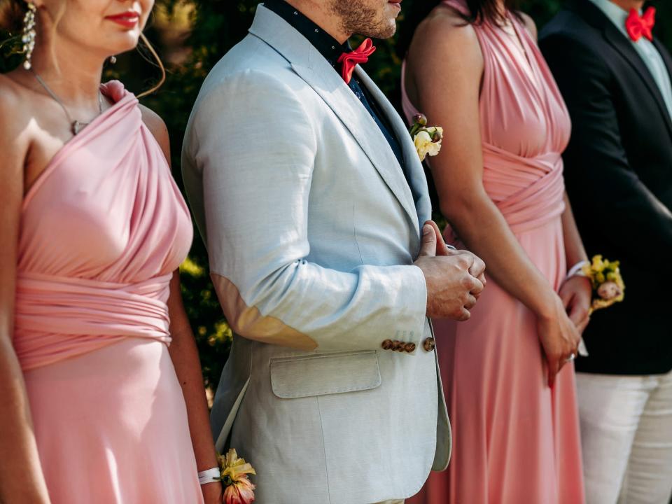 Guests of wedding party lined up in pink dresses and neutral suits