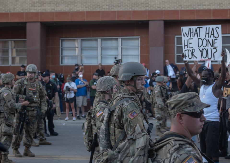 Members of the National Guard stand in formation as protesters march and protest near the BOK Center in Tulsa, Oklahoma on June 20,2020. - Hundreds of supporters lined up early for Donald Trump's first political rally in months, saying the risk of contracting COVID-19 in a big, packed arena would not keep them from hearing the president's campaign message. (Photo by SETH HERALD / AFP) (Photo by SETH HERALD/AFP via Getty Images)