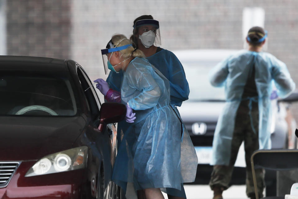 FILE - In this July 14, 2020, file photo, a health worker performs a COVID-19 test at a Test Iowa site at Waukee South Middle School in Waukee, Iowa. South Dakota, Idaho and Iowa are seeing sky-high rates of tests coming back positive. (AP Photo/Charlie Neibergall, File)