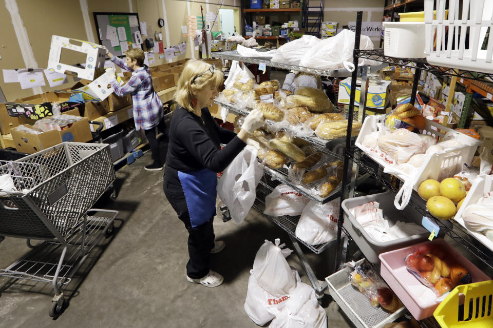 In this April 9, 2020, photo, workers select items to be given to a family at GraceWorks Ministries food pantry in Franklin, Tenn. In addition to finding ways to meet the spike in demand, food banks have had to devise creative new ways to distribute ever greater amounts of food while keeping both recipients and their staff safe from exposure to the coronavirus. (AP Photo/Mark Humphrey)
