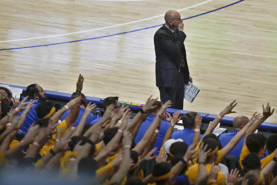 Louisville coach Chris Mack, top watches while the fans in the Pittsburgh student section hold up their hands while Pittsburgh's Justin Champagnie shoots one of the foul shots resulting from the technical foul called on Mack during the second half of an NCAA college basketball game, Tuesday, Jan. 14, 2020, in Pittsburgh. (AP Photo/Keith Srakocic)