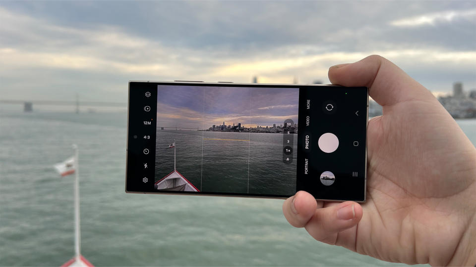 Samsung Galaxy S24 Ultra held horizontally filming a cityscape from across a river water