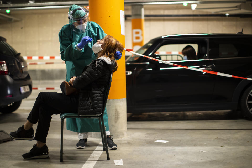 FILE - In this Monday, Aug. 31, 2020 file photo, a member of medical personnel takes a nose swab sample from a patient to be tested for coronavirus at a drive-in test station at the MontLegia CHC hospital in Liege, Belgium. This week news struck that the European Center for Disease Control has put Belgium at the largest number of COVID-19 cases per 100,000 citizens, surpassing the Czech Republic, it is revealed Tuesday Oct. 27, 2020. (AP Photo/Francisco Seco, File)