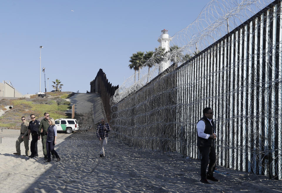 Secretary of Homeland Security Kirstjen Nielsen, left in light blue shirt and blue vest, walks with immigration officials along the border wall separating Tijuana, Mexico, and San Diego, Tuesday, Nov. 20, 2018, in San Diego. Nielsen said Tuesday an appeal will be filed on the decision by a judge to bar the Trump administration from refusing asylum to migrants who cross the southern border illegally. (AP Photo/Gregory Bull)