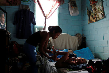 Alejandra Jordan, 30, dresses her son Josue, before her sterilization surgery, at her home in San Francisco de Yare, Venezuela July 11, 2016. REUTERS/Carlos Garcia Rawlins