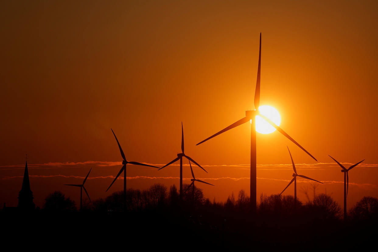 Power-generating windmill turbines and the church of the village are pictured during sunrise at a wind park in Vermandovillers, France, February 28, 2023. REUTERS/Pascal Rossignol