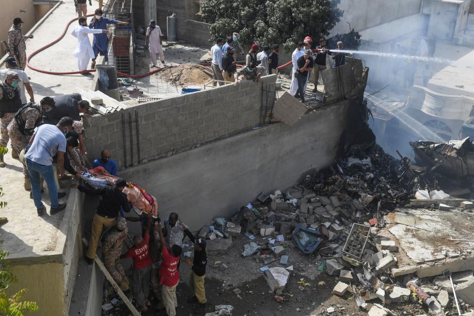 Rescue workers move a body from the site after a Pakistan International Airlines aircraft after crashed at a residential area in Karachi on May 22, 2020. - A Pakistan passenger plane with more than 100 people believed to be on board crashed in the southern city of Karachi on May 22, the country's aviation authority said. (Photo by Asif HASSAN / AFP) (Photo by ASIF HASSAN/AFP via Getty Images)