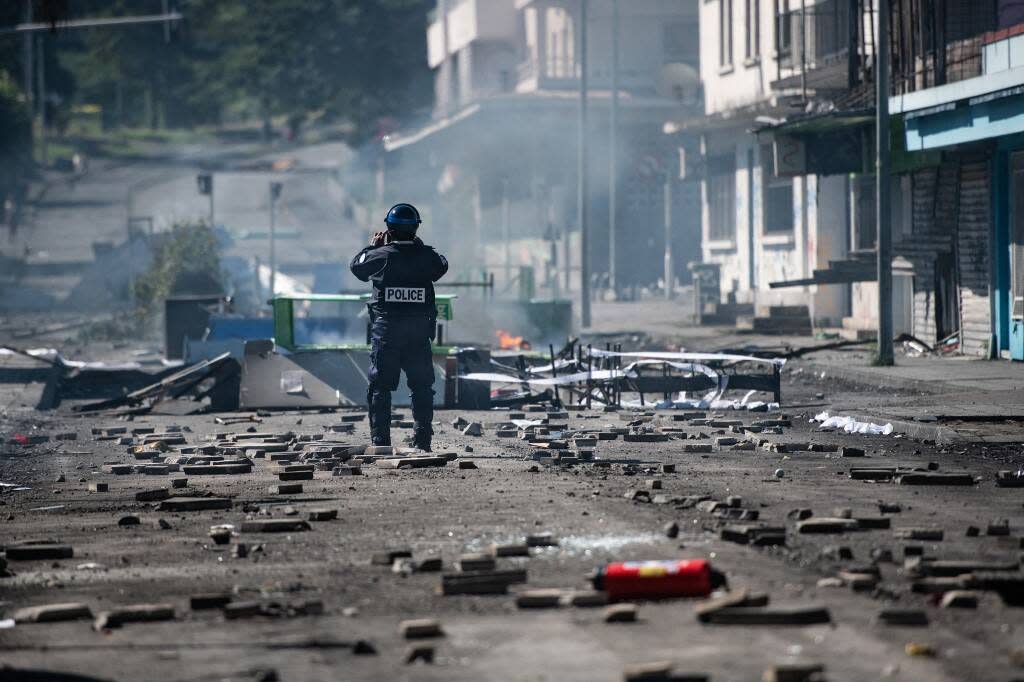 Un membre de la police française prend des photos d’un barrage routier mis en place par des indépendantistes à Nouméa, en Nouvelle-Calédonie, le 24 juin 2024.