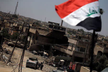 Destroyed buildings are seen in the background as an Iraqi national flag flutters at the frontline in western Mosul, Iraq June 4, 2017. REUTERS/Alkis Konstantinidis