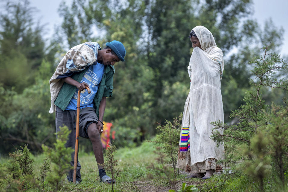 Militia fighter Abebaw Adugna, left, shows his wound to a woman from his hometown of Addi Arkay at a center for the internally-displaced in Debark, in the Amhara region of northern Ethiopia Friday, Aug. 27, 2021. Adugna was shot by Tigrayan forces during a fight for his town and the bullet is still in his leg. As they bring war to other parts of Ethiopia such as the Amhara region, resurgent Tigray fighters face growing allegations that they are retaliating for the abuses their people suffered back home, sending hundreds of thousands of people fleeing in the past two months. (AP Photo/Mulugeta Ayene)