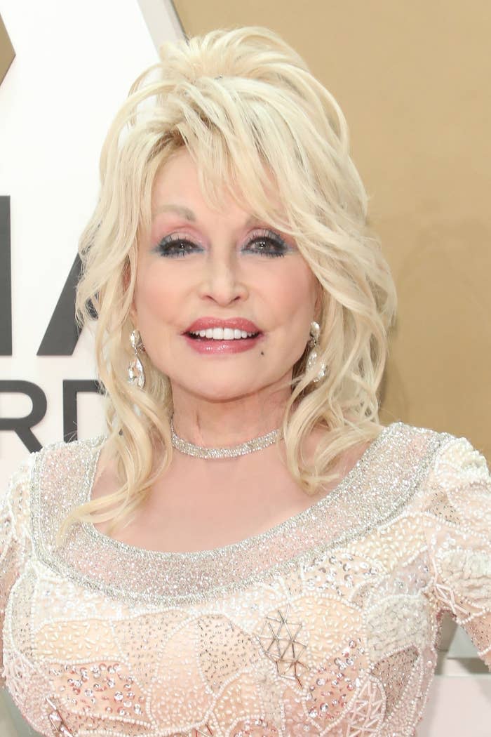Dolly Parton smiles at a red carpet event while wearing a dress
