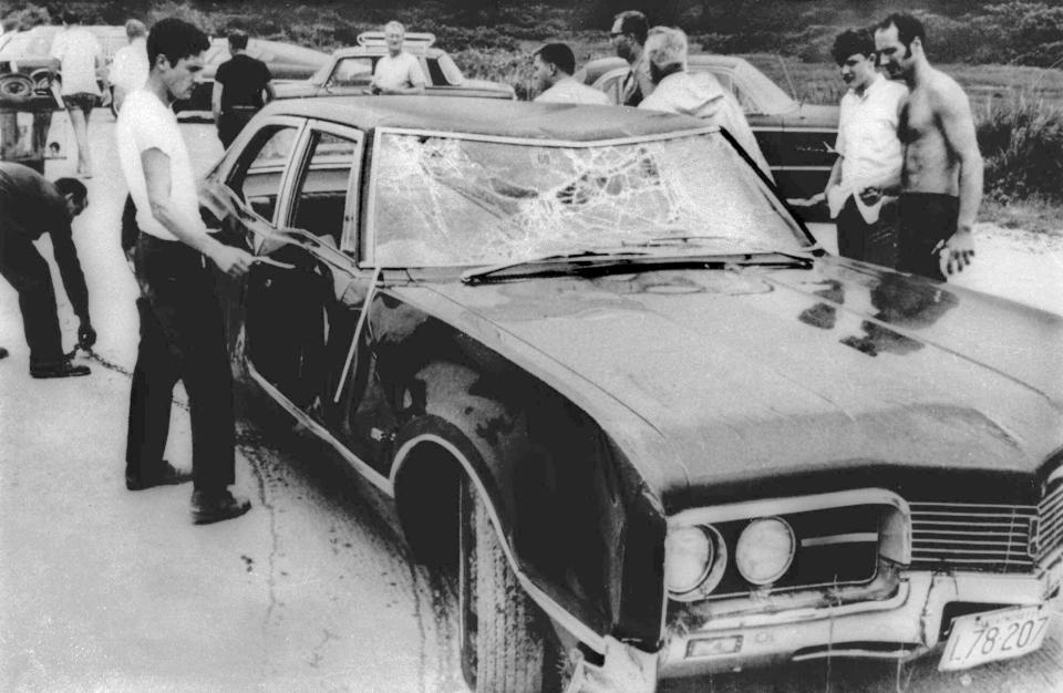 FILE - In this July 18, 1969 file photograph, curious onlookers inspect U.S. Sen. Edward Kennedy's car in Edgartown, Mass. Mary Jo Kopechne drowned after Kennedy drove the car off Dyke Bridge on Chappaquiddick Island, Mass. on July 18, 1969. It's been 50 years since the fateful automobile accident that killed a woman and thwarted Kennedy's presidential aspirations. (AP Photo, File)