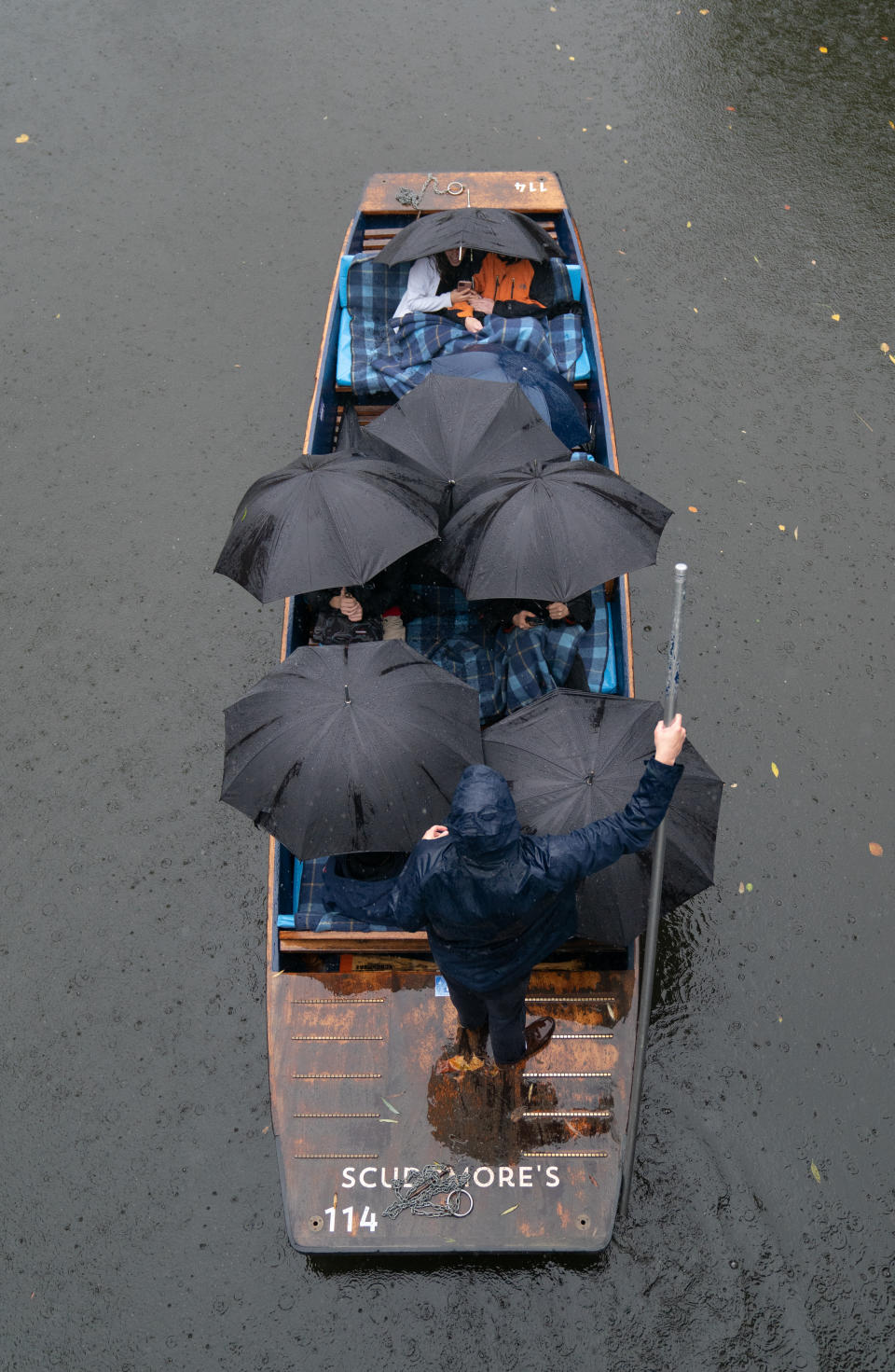 People sheltered under umbrellas as they punted on the River Cam in Cambridge during heavy rain on Sunday. (PA)