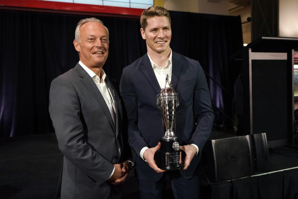 Fred Lissalde, left, president and CEO of BorgWarner stands with driver Josef Newgarden, winner of the 2023 Indianapolis 500, as Newgarden holds the Baby Borg trophy, Tuesday, Jan. 23, 2024 in Dearborn, Mich. (AP Photo/Carlos Osorio)