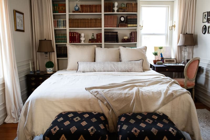 Decorative pillows on neatly made bed in renovated bedroom.