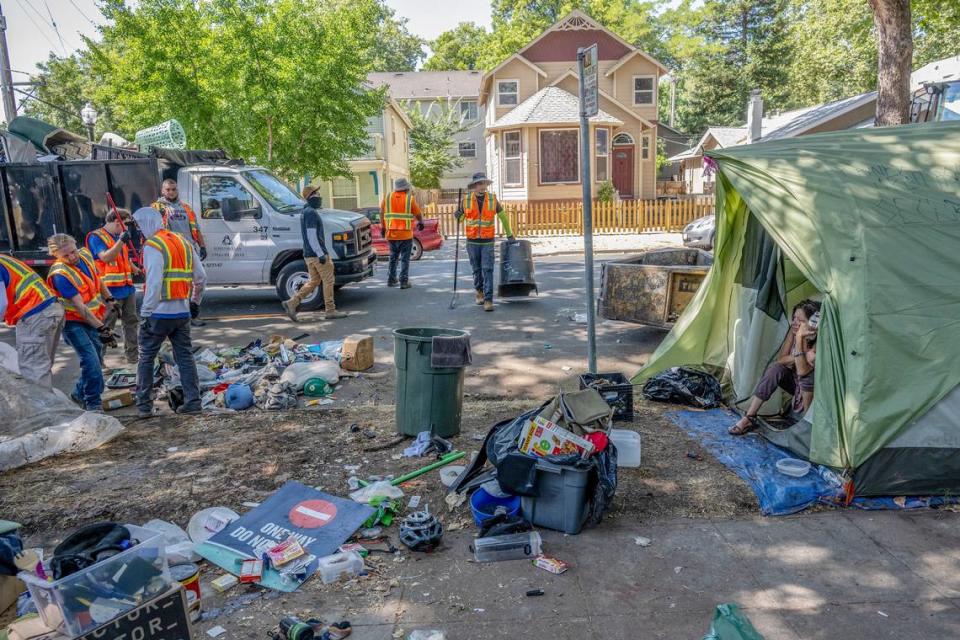 Alicia Peterson, 55, watches as contract workers for the city of Sacramento discard the belongings of neighboring campers during a homeless sweep on C Street in Sacramento on July 19. Renée C. Byer/rbyer@sacbee.com