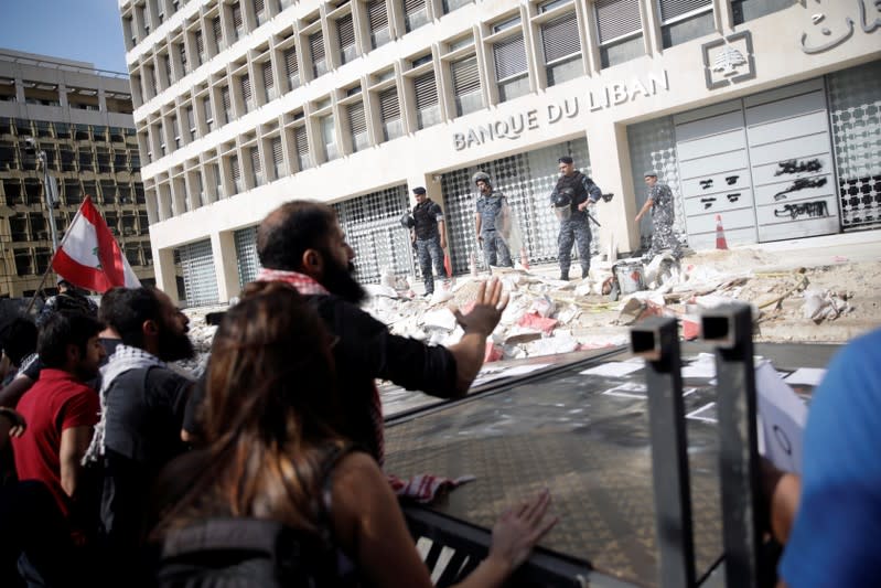 Police officers stand guard as protesters knocked down the fencing as they demonstrate outside of Lebanon Central Bank during ongoing anti-government protests in Beirut