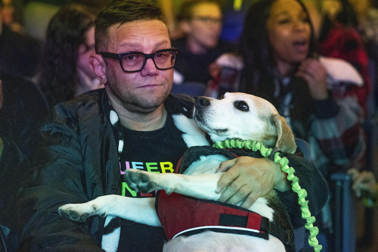 British intersex activist, comedian Seven Graham hugs his Beagle service dog, "Scotty," as they attend a memorial for the victims of Saturday's fatal shooting at Club Q in Colorado Springs, Colo., at the Transgender Day of Remembrance event in West Hollywood, Calif., Sunday night, Nov. 20, 2022. (AP Photo/Damian Dovarganes)