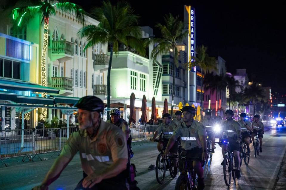 Police officers ride bikes down Ocean Drive before the start of a midnight curfew during spring break on Friday, March 15, 2024, in Miami Beach, Fla.