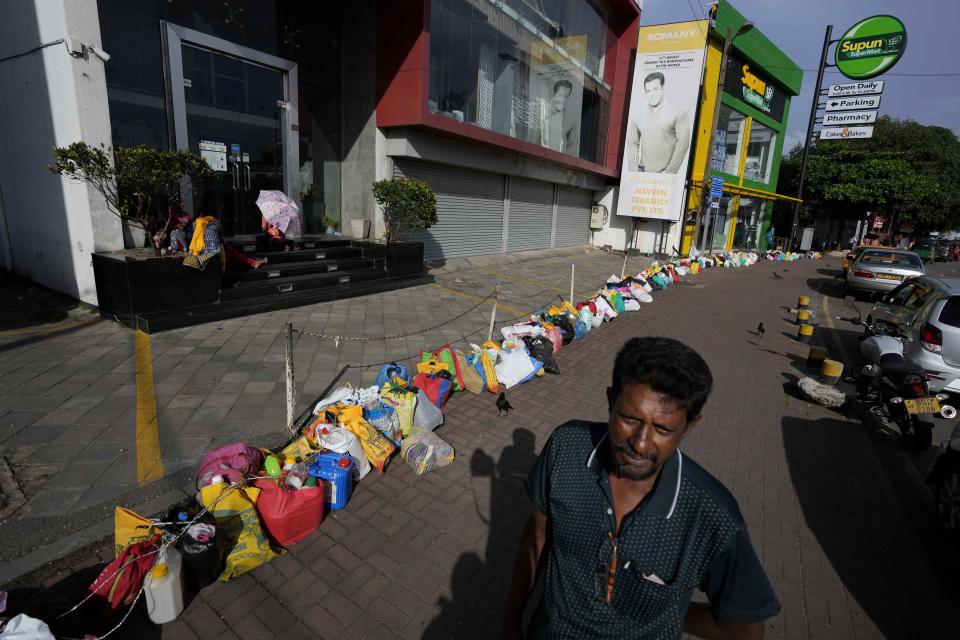 A man waits to buy kerosene oil standing by a line of empty canisters placed outside a fuel station amid shortage of cooking gas in Colombo, Sri Lanka, Thursday, June 23, 2022. Sri Lankans have endured months of shortages of food, fuel and other necessities due to the country’s dwindling foreign exchange reserves and mounting debt, worsened by the pandemic and other longer term troubles. (AP Photo/Eranga Jayawardena)