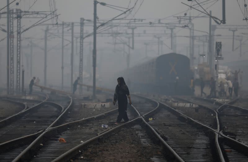 FILE PHOTO: A woman crosses a railway line on a smoggy morning in New Delhi