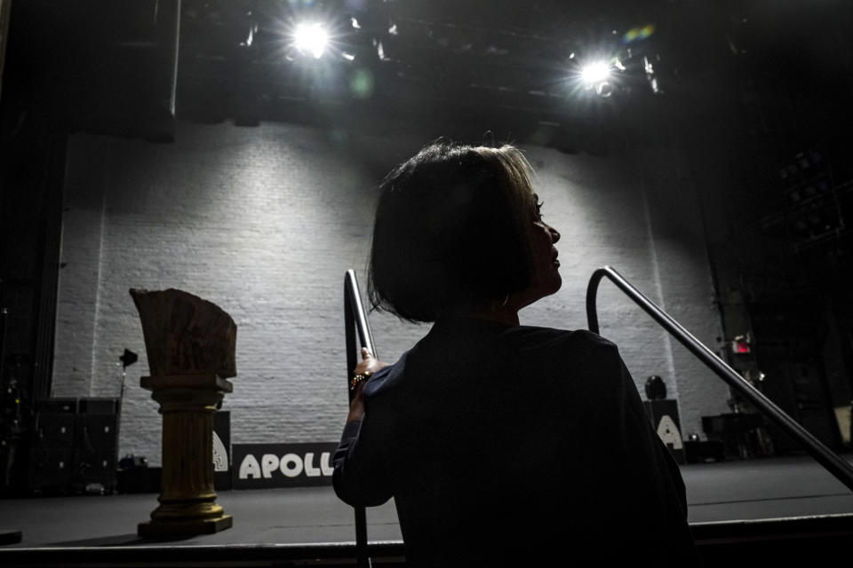 Apollo President and CEO Jonelle Procope is silhouetted next to the iconic "Tree Of Hope" stump, left, which entertainers rub for good luck before a performance, while posing near the stage at the Apollo Theatre, Monday June 5, 2023, in New York. Procope, who will be ending her 20-year run leading the organization on June 12, has been critical in fundraising for the theater's restoration to its former glory. (AP Photo/Bebeto Matthews)
