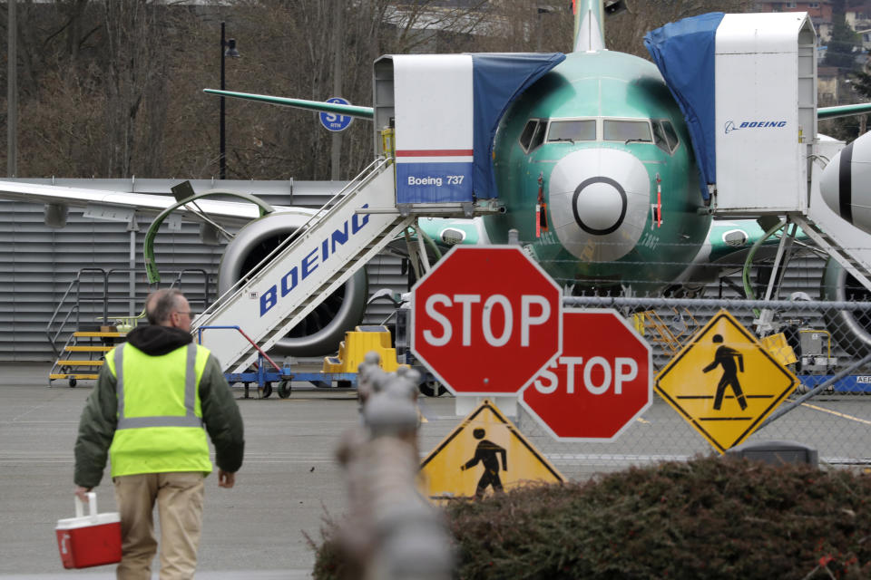 FILE - In this Monday, Dec. 16, 2019 file photo, a Boeing worker walks in view of a 737 MAX jet in Renton, Wash. Shares of Boeing fell before the opening bell on a report that the company may cut production of its troubled 737 MAX or even end production all together. (AP Photo/Elaine Thompson)