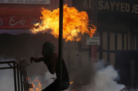 A masked Palestinian throws a molotov cocktail at Israeli troops during clashes in the West Bank city of Hebron October 9, 2015. REUTERS/Mussa Qawasma