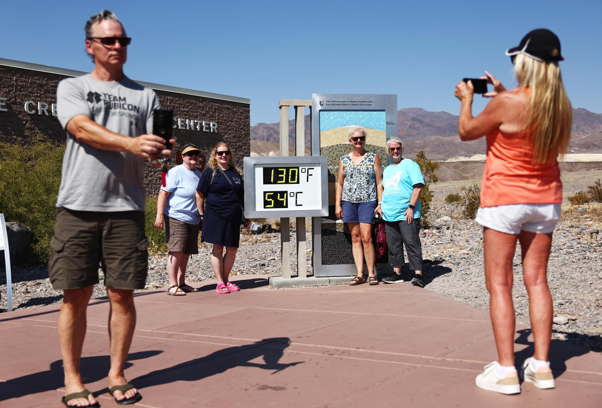 Tourists take photos at an unofficial thermometer at Furnace Creek Visitor Center.