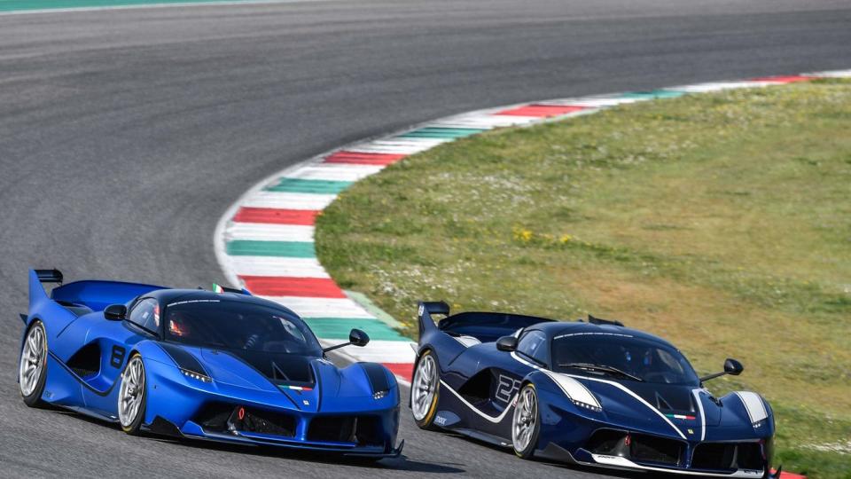 two blue ferrari sports cars on a race track