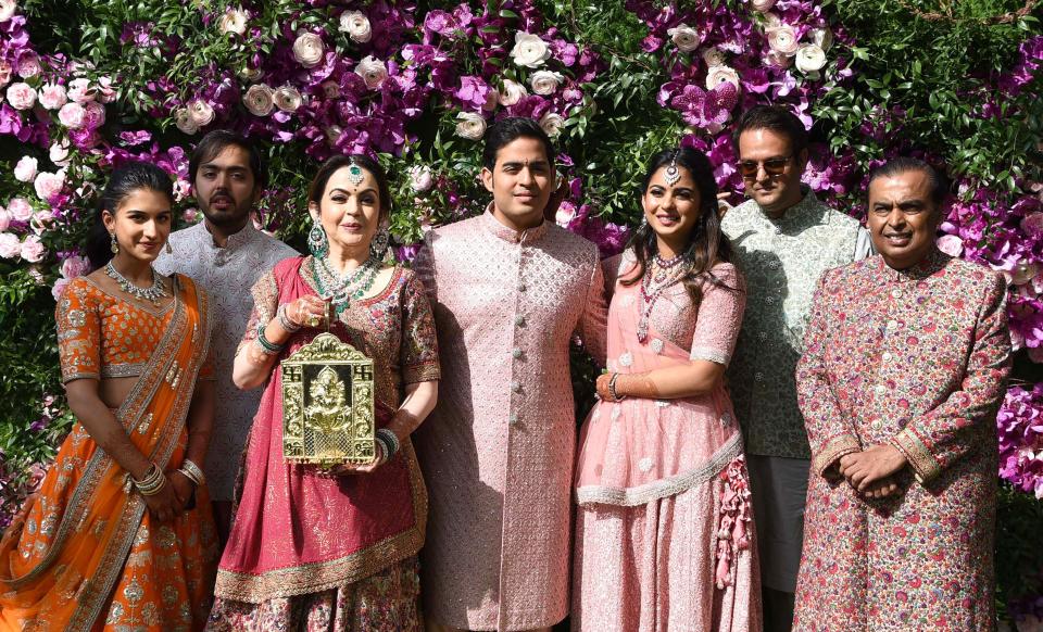 Akash Ambani (C), son of Indian businessman Mukesh Ambani (R) and businesswoman Nita Ambani (3rd L), their daughter Isha Ambani (3rd R) and her husband Anand Piramal (2nd R) pose during the wedding ceremony of Akash Ambani in Mumbai on March 9, 2019.
