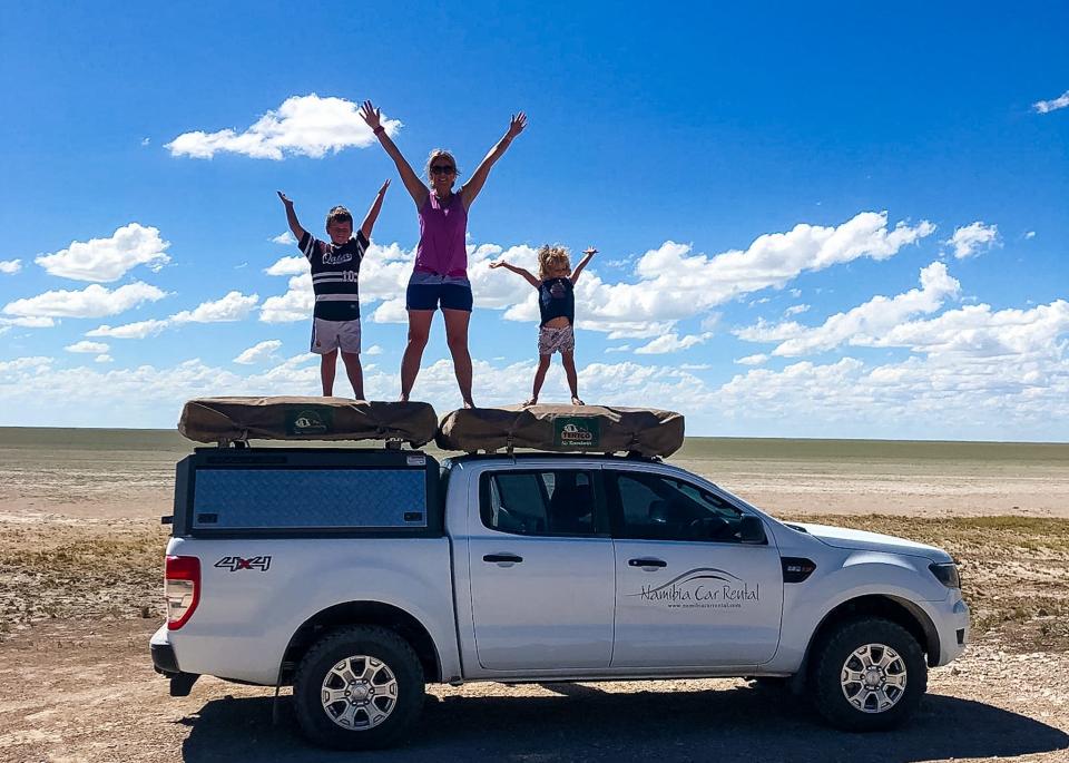 Mother and two children standing on top of 4x4 car in Namibia