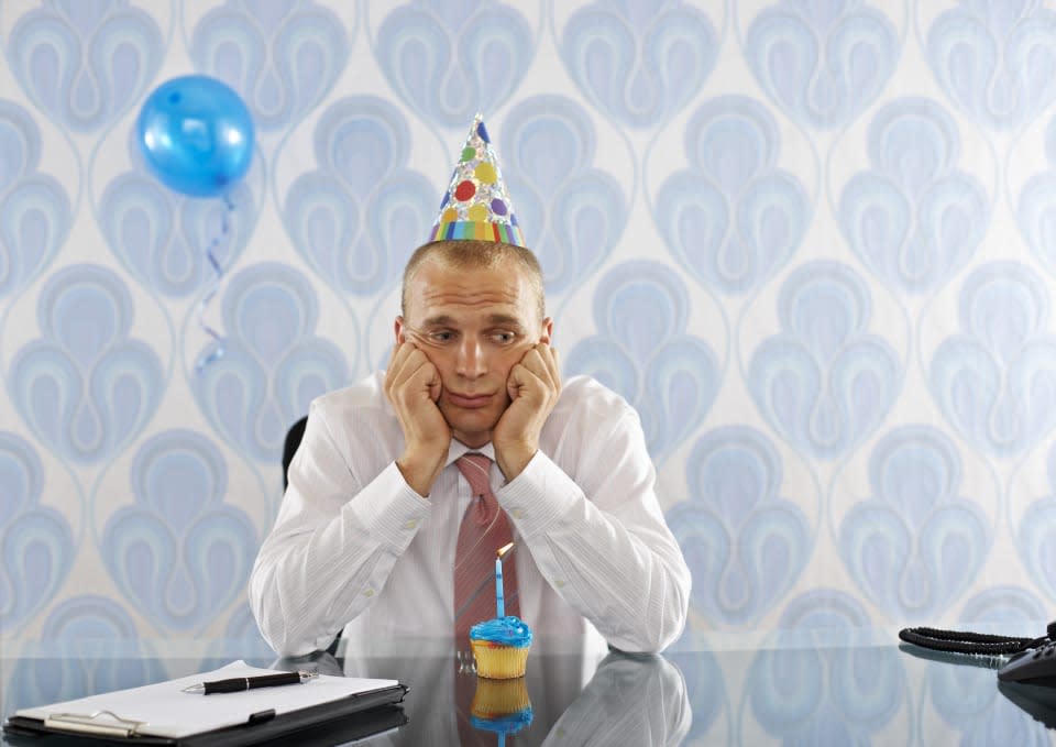 Sad Businessman at Desk Wearing Party Hat